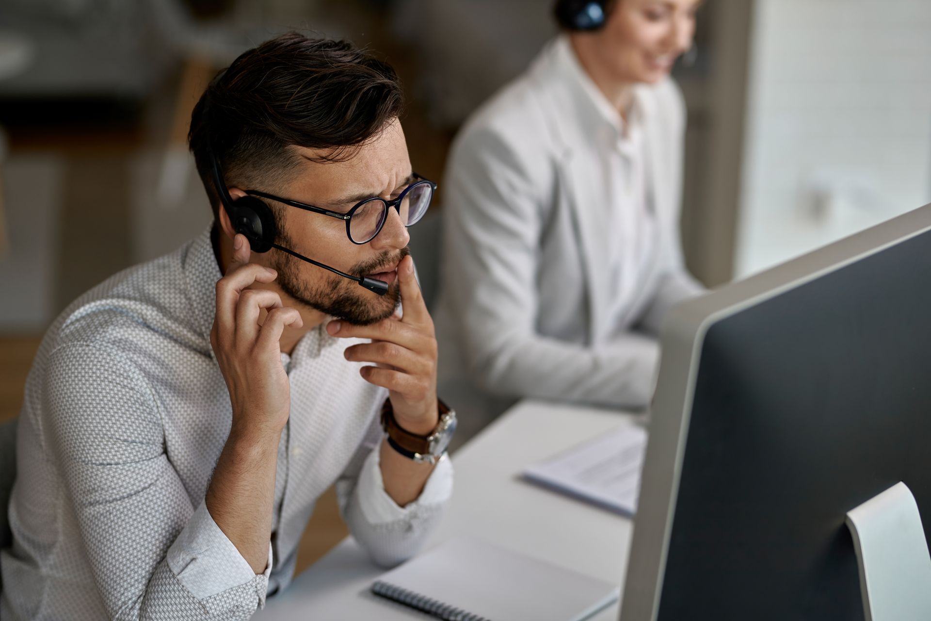 On voit un homme au premier plan qui répond au téléphone. Une femme est également présente au second plan et travaille sur son ordinateur. L'agence de communication à Baccarat dans le 54 JVFlex utilise cette photo afin d'imager l'offre de formation qu'elle propose.